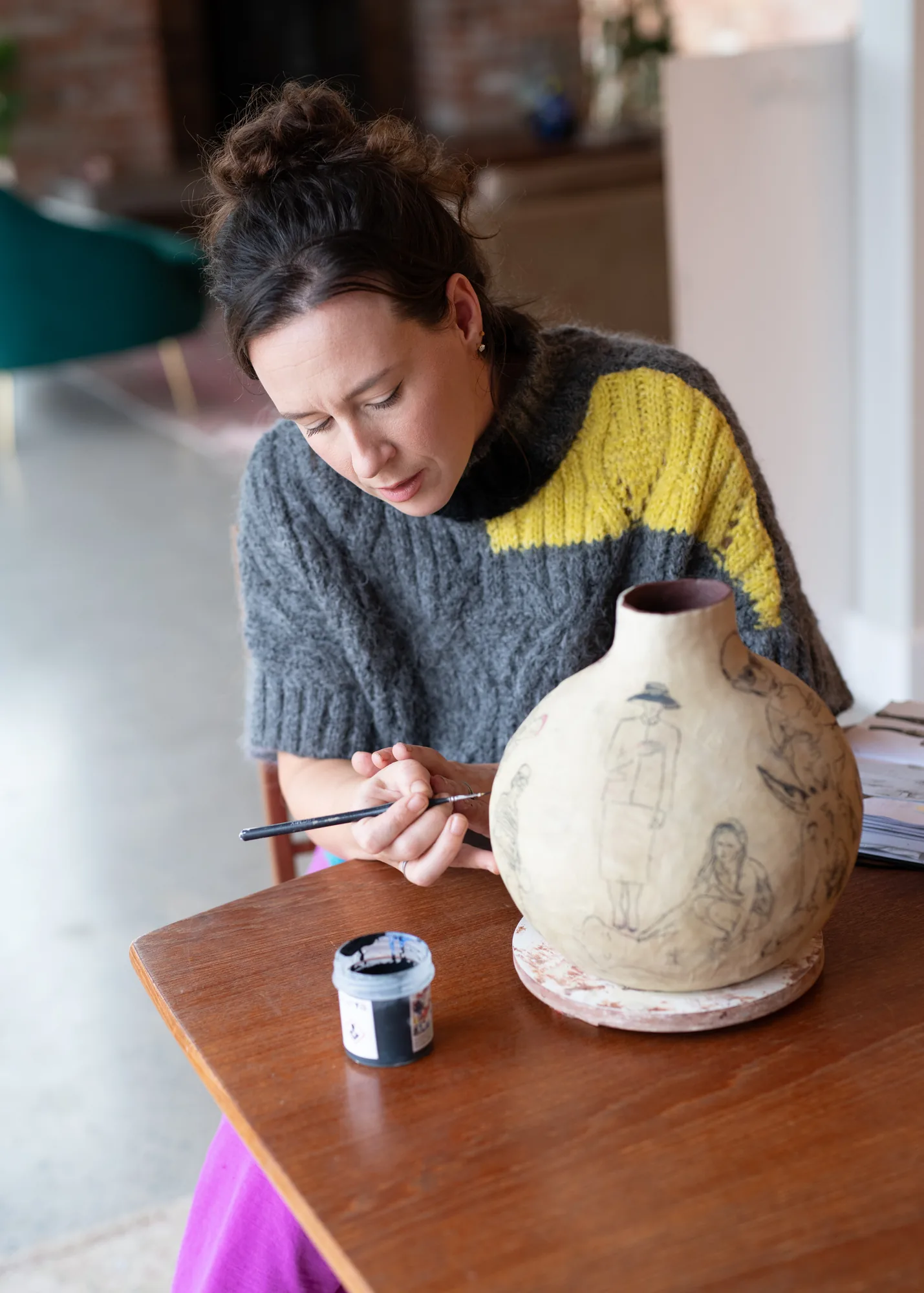 Suzanne Dolan painting a hand-built vessel at her table
